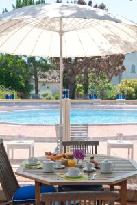 uma mesa com um guarda-chuva ao lado de uma piscina em Résidence Domaine De Caranella em Porto-Vecchio