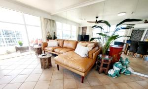 a living room with a leather couch and a plant at 19th Avenue on the Beach in Gold Coast