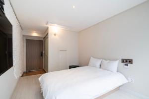 釜山的住宿－艾麗西亞精品酒店，卧室设有白色的床和走廊