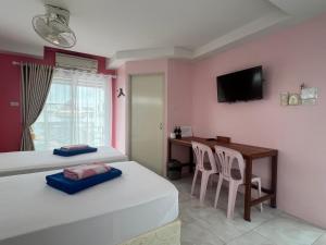 a bedroom with two beds and a desk and a television at Bonita House in Bangkok
