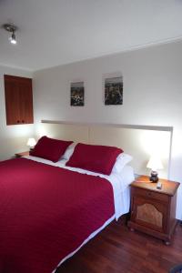 um quarto com uma cama grande e um cobertor vermelho em San Ignacio Suite em Santiago