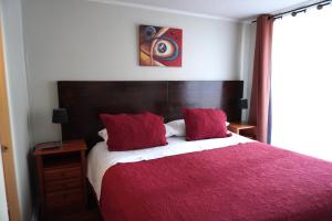 a bedroom with a large bed with a red blanket at San Ignacio Suite in Santiago