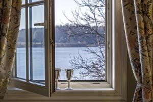 deux verres assis sur un rebord de fenêtre donnant sur l'eau dans l'établissement Argo Trakai, à Trakai