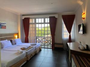 um quarto de hotel com duas camas e uma grande janela em Bella Vista Express Hotel em Pantai Cenang