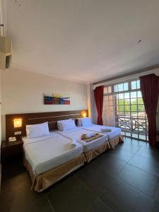 a large bed in a bedroom with a large window at Bella Vista Express Hotel in Pantai Cenang
