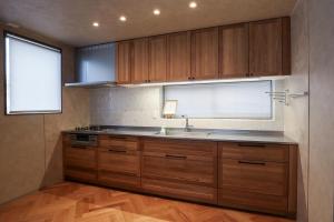 Una cocina con armarios de madera y un fregadero y una ventana. en 金沢四季亭, en Housai