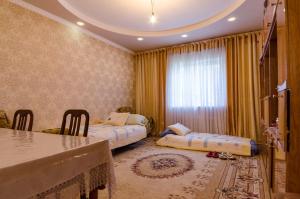 a bedroom with two beds and a table and chairs at ilim-mahabat in Bishkek