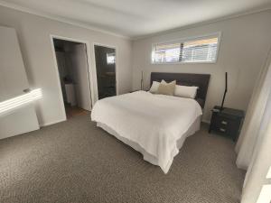 a bedroom with a large white bed and a window at Karapiro Apartment in Cambridge +18 photos