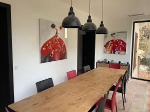 una sala da pranzo con tavolo in legno e sedie rosse di Villa provençale, 8 personnes, très grande piscine et jardin, au calme, salle de fitness et espace coworking a Opio