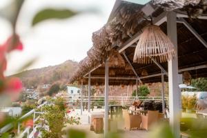 a patio with a straw umbrella and chairs and tables at Ananas Beach Hotel in Vung Tau