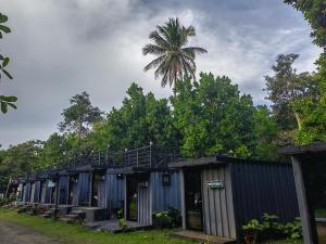 a row of blue buildings with a palm tree in the background at Kaliraya Surf Kamp by Eco Hotel Laguna in Cavinti