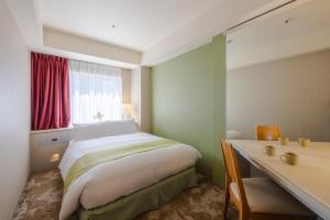 a bedroom with a bed and a desk and a window at Shinjuku Washington Hotel Annex in Tokyo