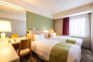 a hotel room with two beds and a desk at Shinjuku Washington Hotel Annex in Tokyo