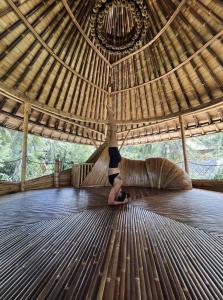 a woman doing a handstand on a wooden floor in a hut at Cacao House 4bds Eco Bamboo House, pool, near Green School Bali in Bringkit