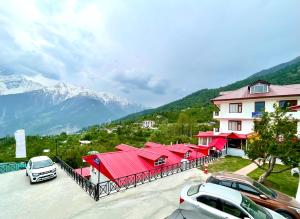 a building with red roofs and cars parked in a parking lot at Hotel Rollingrang in Kalpa