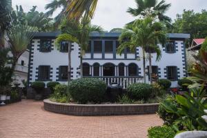 un bâtiment blanc avec des palmiers devant lui dans l'établissement Hotel Chateau St Cloud, à La Digue