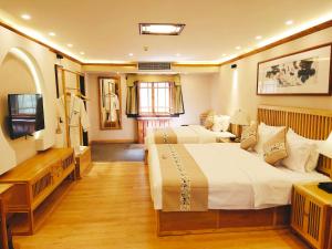 a hotel room with two beds and a television at Yangshuo Ancient Garden Boutique Hotel in Yangshuo
