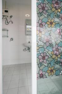a bathroom with a shower with a floral shower curtain at V Hotel Vientiane in Vientiane