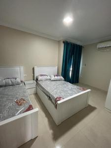 two beds in a bedroom with blue curtains at 4Bedroom villa in pharos in Mountain view 98 B in Zāwiyat al ‘Awwāmah