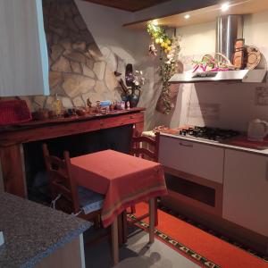 a kitchen with a stove and a table with a stool at ANTICA BAITA in Gergei