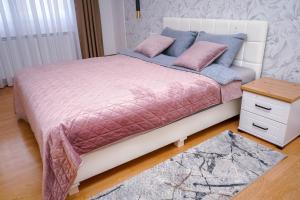 een bed met roze en blauwe lakens en een tafel bij Apartman Mona in Teslić