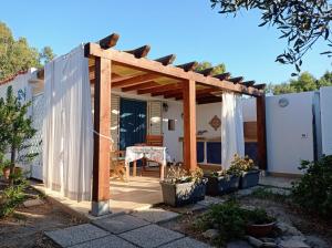 a pergola with a table on a patio at Cottage a 1km dal centro storico, 500 m dal mare,veranda attrezzata, giardino,vista mare in Carloforte