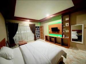 sypialnia z dużym białym łóżkiem i telewizorem w obiekcie Jelita Beach Mentawai w mieście Tua Pejat
