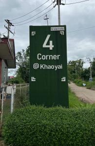 un letrero verde para un pueblito de la esquina en 4 Corner Khaoyai en Mu Si