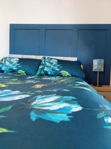 a bedroom with a blue bed with a blue headboard at 'Serenity in Somerset' , Scenic Views across Dorset , Half a mile from Devon & Close to the Jurassic Coast without the Hustle & Bustle in Chardstock