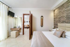 a bedroom with a white bed and a brick wall at Mandani Villa Luxury Apartments in Limenas
