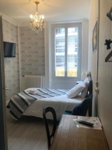 a bedroom with a bed and a window and a table at Hôtel Continental in Évian-les-Bains