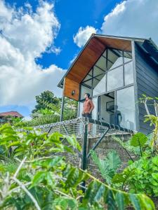 Ein Mann steht auf der Treppe eines winzigen Hauses in der Unterkunft Alam Kita Glamping & Plantation in Munduk