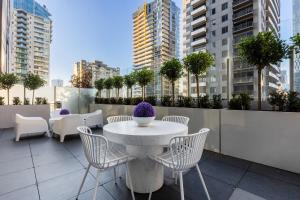 einen Tisch und Stühle auf einem Balkon mit Gebäuden in der Unterkunft VAQUAY Valentino In Southbank in Melbourne