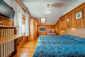 1 dormitorio con 1 cama azul y TV en Appartamenti Pagan, en San Vito di Cadore