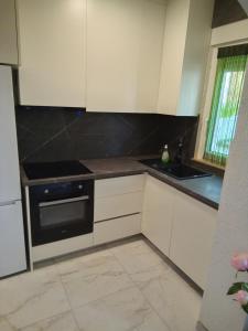 a kitchen with white cabinets and a black oven at Apartman Pavic in Pag
