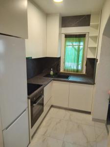 a kitchen with white cabinets and a window at Apartman Pavic in Pag
