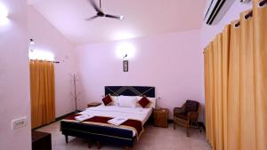 a bedroom with a bed and a chair at Kuttralam Resorts in Kuttālam +33 photos