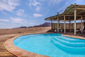 a swimming pool in the desert with a gazebo at Desert Hills Glamping Camp in Sesriem