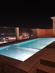 una piscina en la parte superior de un edificio por la noche en Iveria Hotel Apartments en Ḩayl Āl ‘Umayr