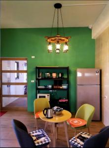 een keuken met een tafel en stoelen en een groene muur bij 星語采居民宿 in Magong