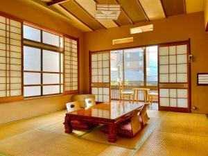 een eetkamer met een tafel, stoelen en ramen bij 日本旅館　松亀荘 in Beppu