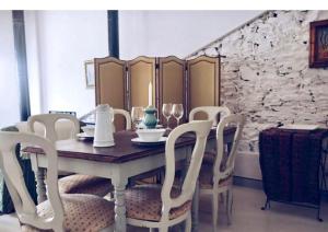 a dining room table with white chairs and a stone wall at Casas de La Ermita VTAR TANA in Puerto-Gil +2 photos