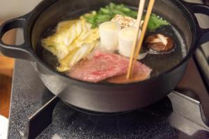 uma panela cheia de comida num fogão com pauzinhos em cyashitsu ryokan asakusa em Tóquio