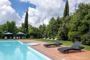 uma piscina com duas espreguiçadeiras e árvores em Rosaspina - Appartamento 1 em Capalbio