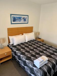 a bedroom with a black and white bed with two night stands at Seahorse Motel Cowes in Cowes