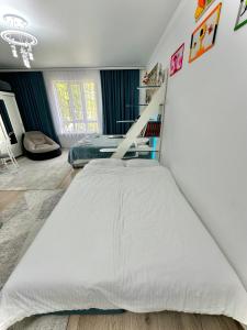 ein Schlafzimmer mit einem großen weißen Bett in einem Zimmer in der Unterkunft Raduga West 'Azure' Apartment in Koshkolʼ