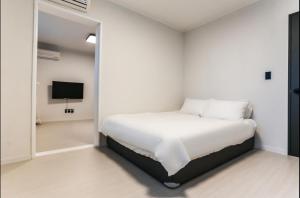 a white bedroom with a bed and a tv at La Famille in Yangyang