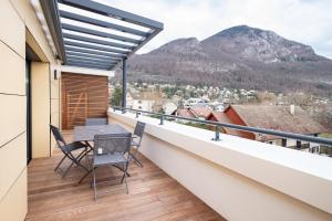 a balcony with a table and chairs and mountains at Printemps chaleureux T4 +2 place de parking privée in Annecy