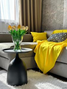 uma sala de estar com um vaso de flores sobre uma mesa em Apartament Almaty Akvarel em Almaty