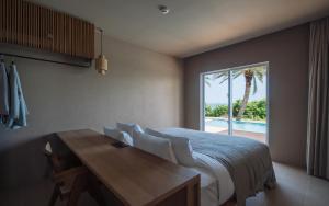 um quarto com uma cama, uma mesa e uma janela em アヤンナ宮古島 em Ilhas Miyako